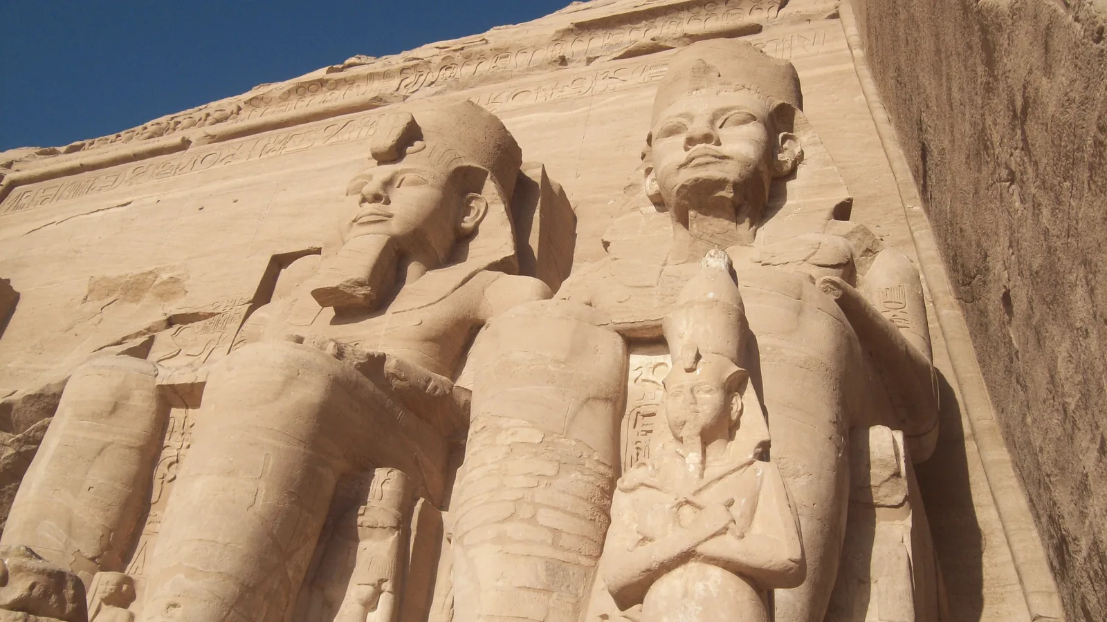 seated colossal stone statues of a pharaoh carved into the sandstone facade of the Great Temple at Abu Simbel