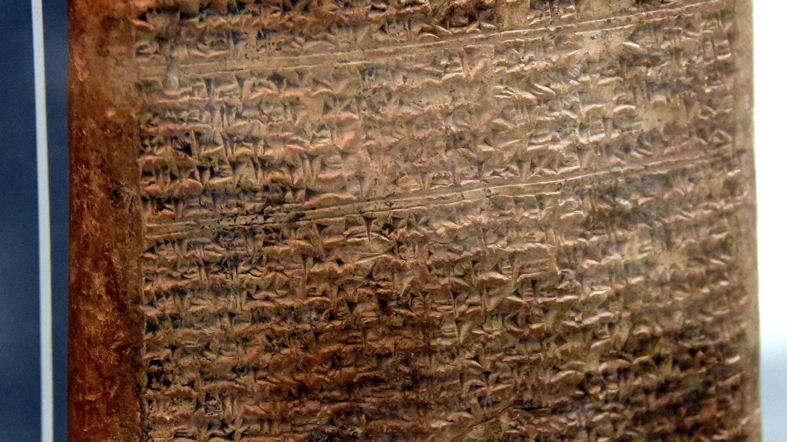 A large clay tablet densely inscribed with cuneiform text, propped upright in a museum display stand