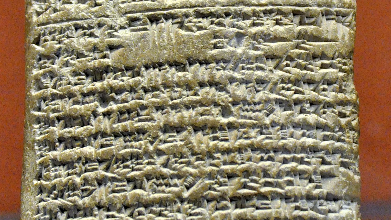 A clay tablet covered in cuneiform Akkadian script, displayed upright in a museum case
