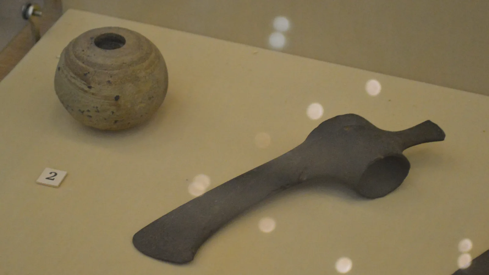 Stone mace and bronze axe from a Sintashta culture cemetery, displayed in a museum case