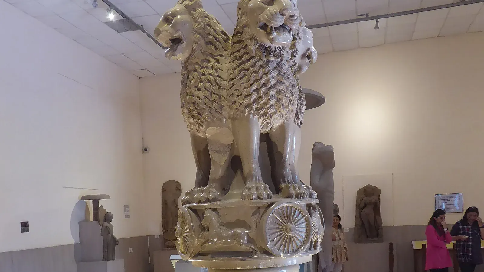 a polished sandstone capital with four lions seated back to back above a wheel frieze