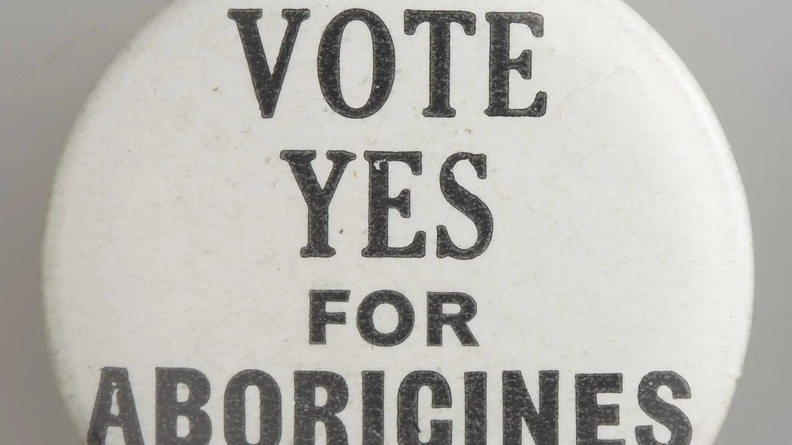 a round white tin badge printed in black capitals with the words vote yes for aborigines