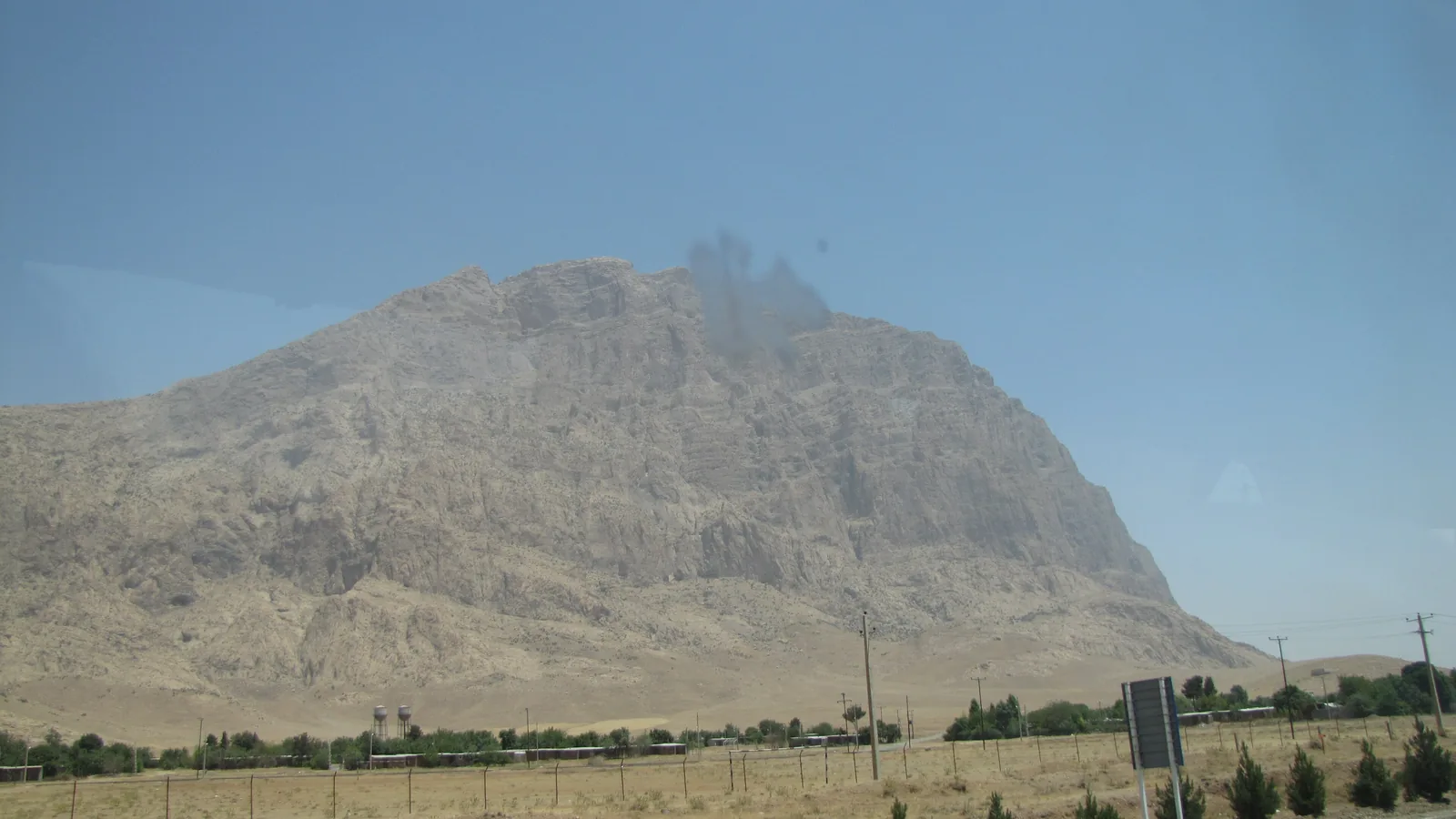 The Bisotun cliff face rising above the surrounding plain near Kermanshah, Iran