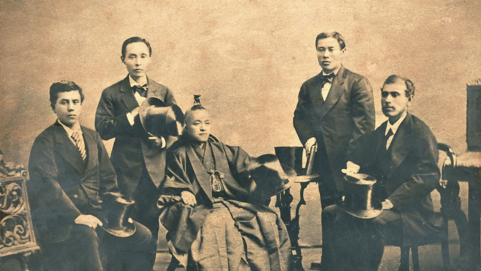 a group photograph of Japanese officials in Western suits and a kimono-clad woman posed formally