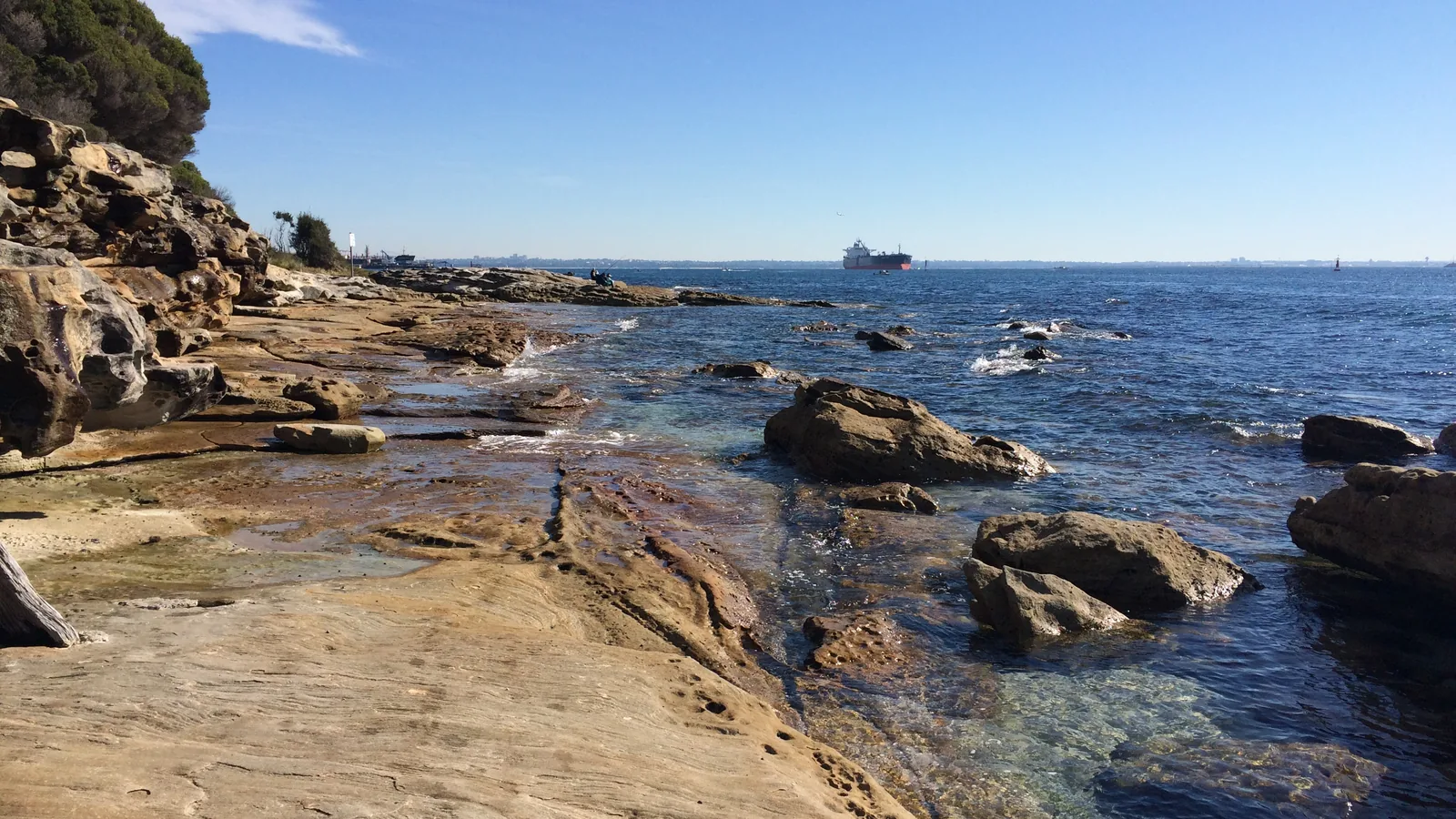 View across a wide open bay with rocky shoreline in the foreground