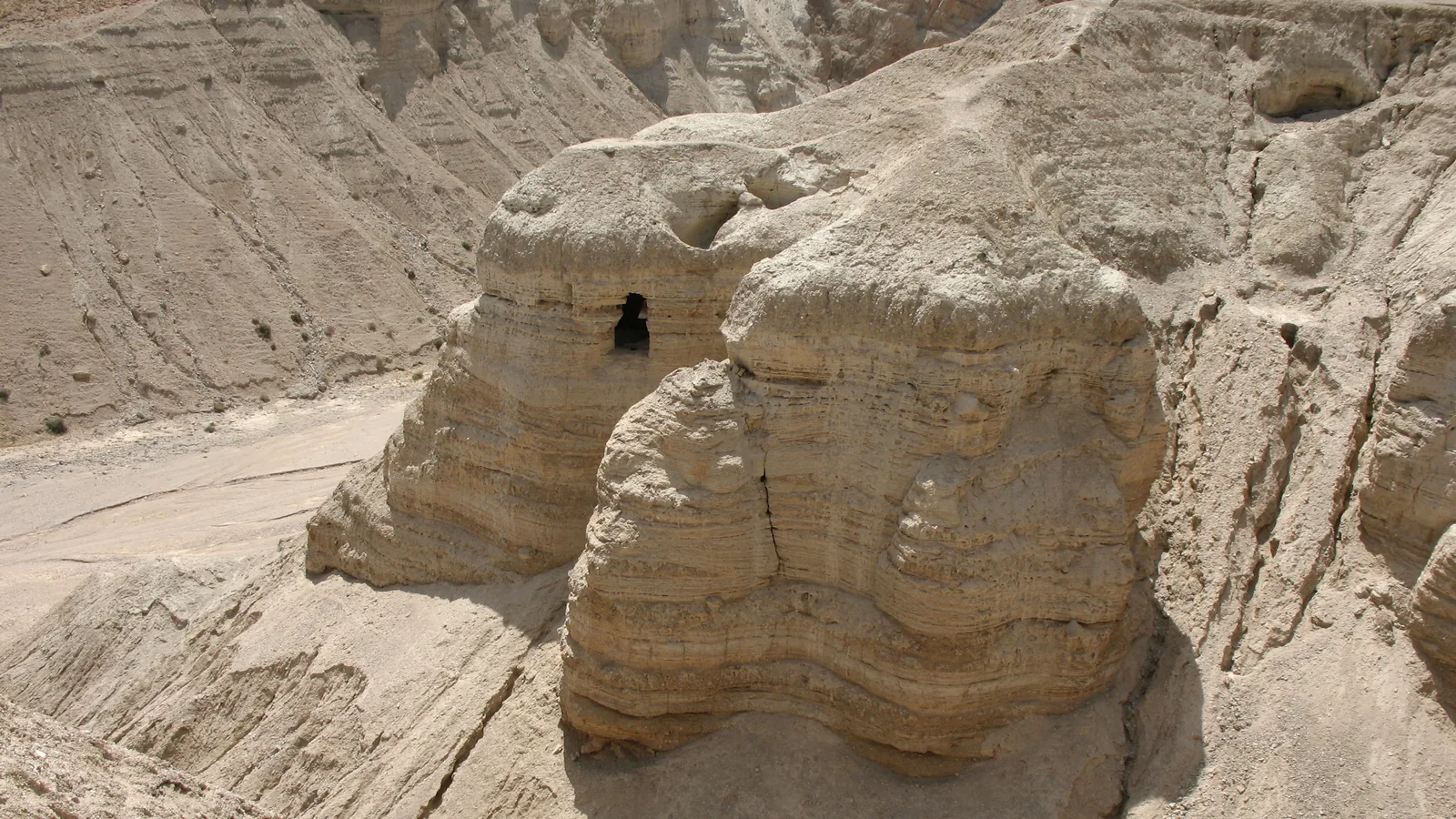 Cliffside caves overlooking a dry valley near the Dead Sea shore