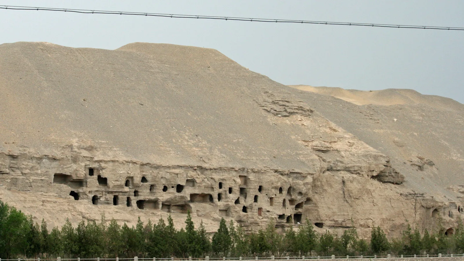 Cliff face honeycombed with cave entrances and wooden walkways