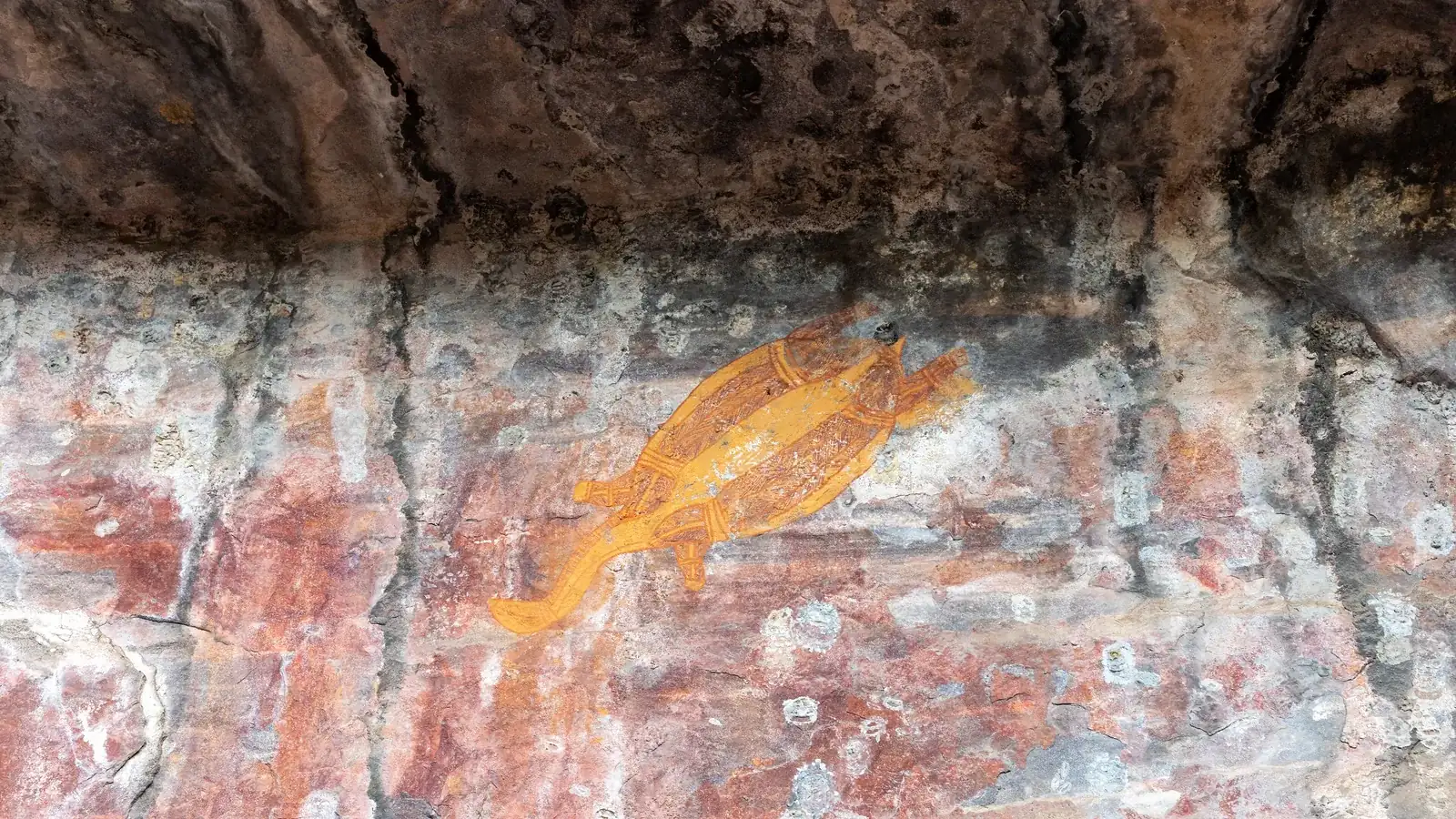 rock art figures painted in red and white on a sandstone overhang