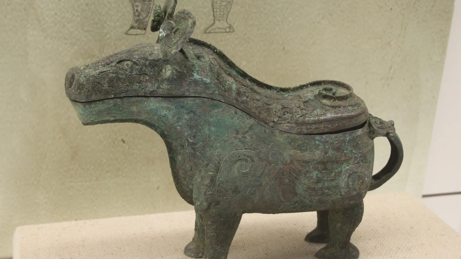 Bronze lidded pouring vessel with animal-mask decoration in a museum case