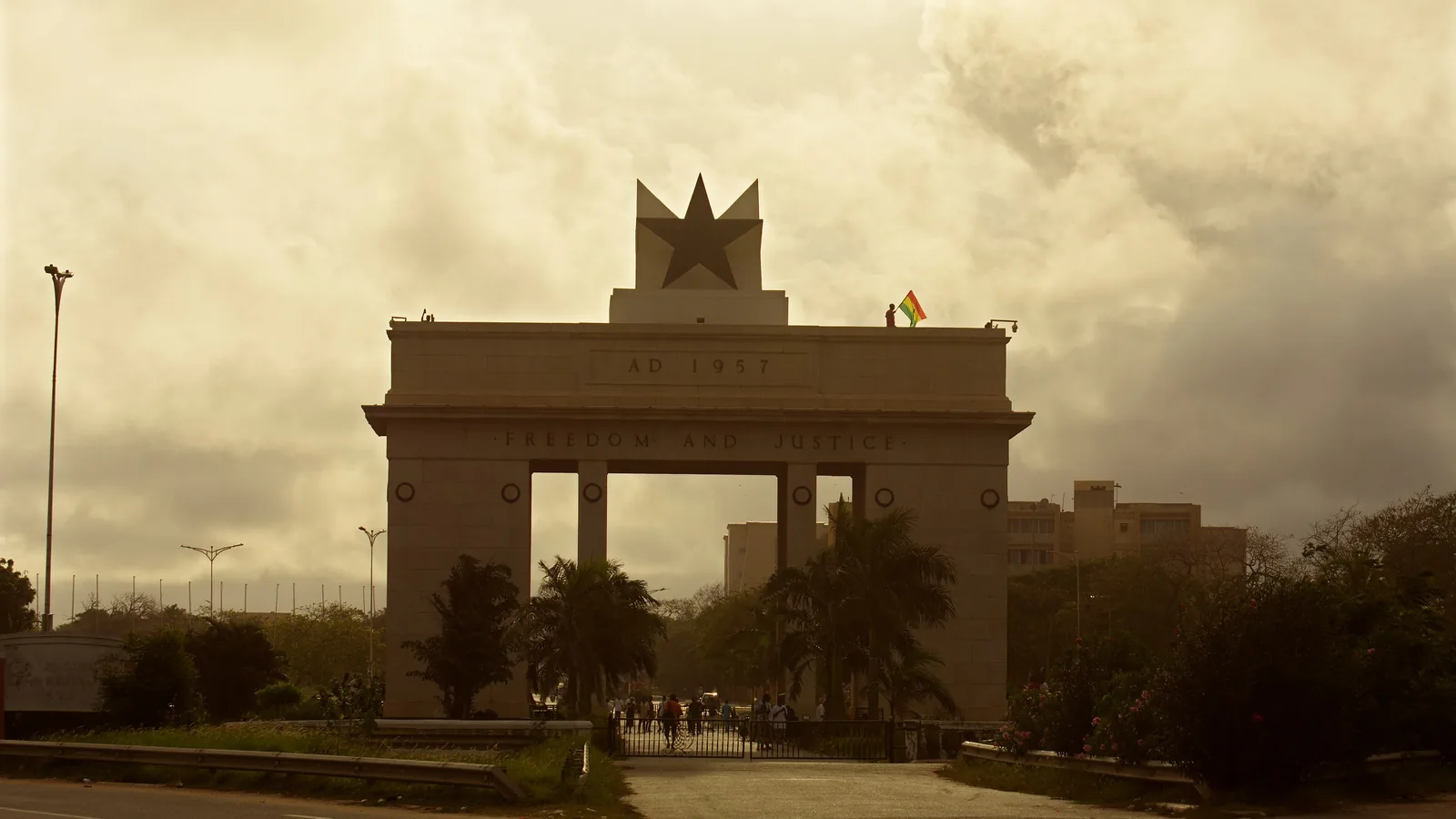 a tall concrete arch with a black star on top, photographed at sunset on an open square
