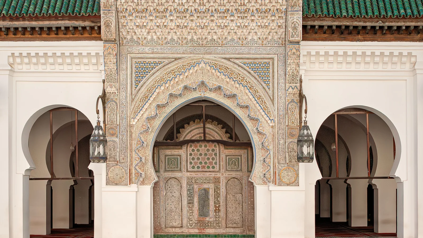 a carved and tiled portal with horseshoe arches in the courtyard of a mosque in Fez