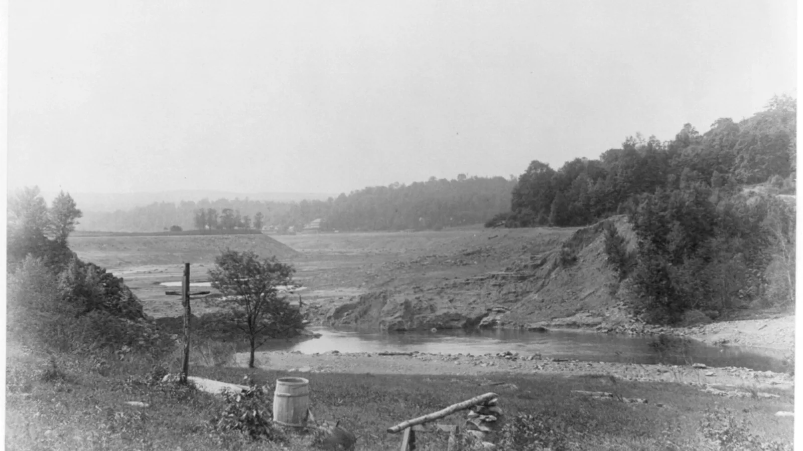 1889 photo of an emptied reservoir valley with a distant clubhouse after a dam failure