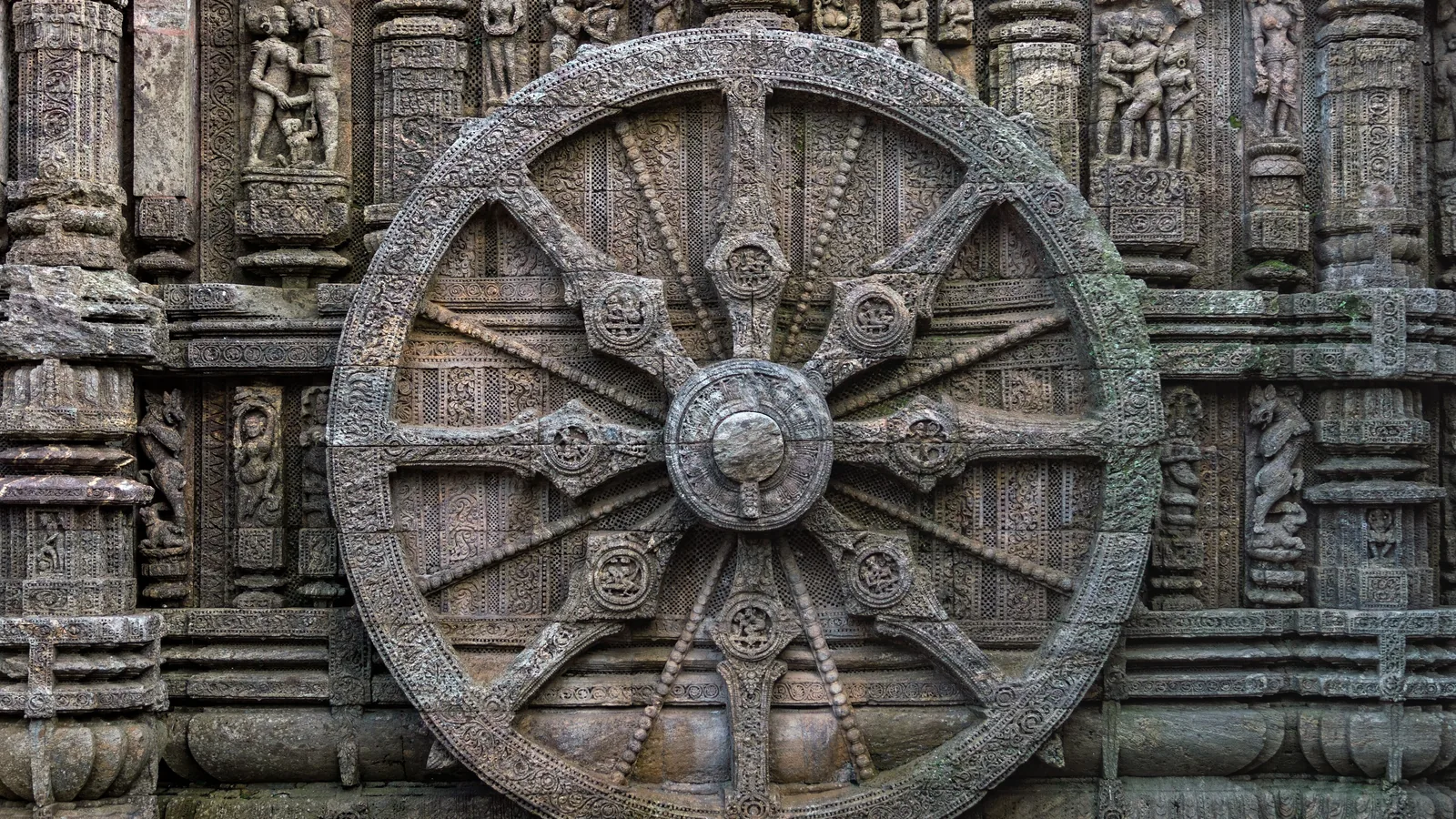 A carved stone wheel with spokes and medallions set into the sculpted base wall of the Konark Sun Temple
