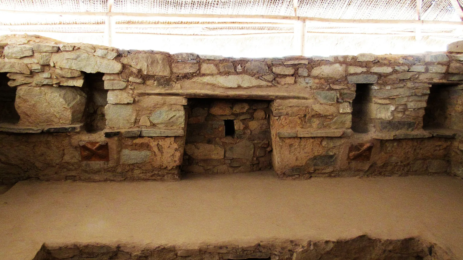 Clay relief of two crossed forearms and hands set into a wall at Kotosh
