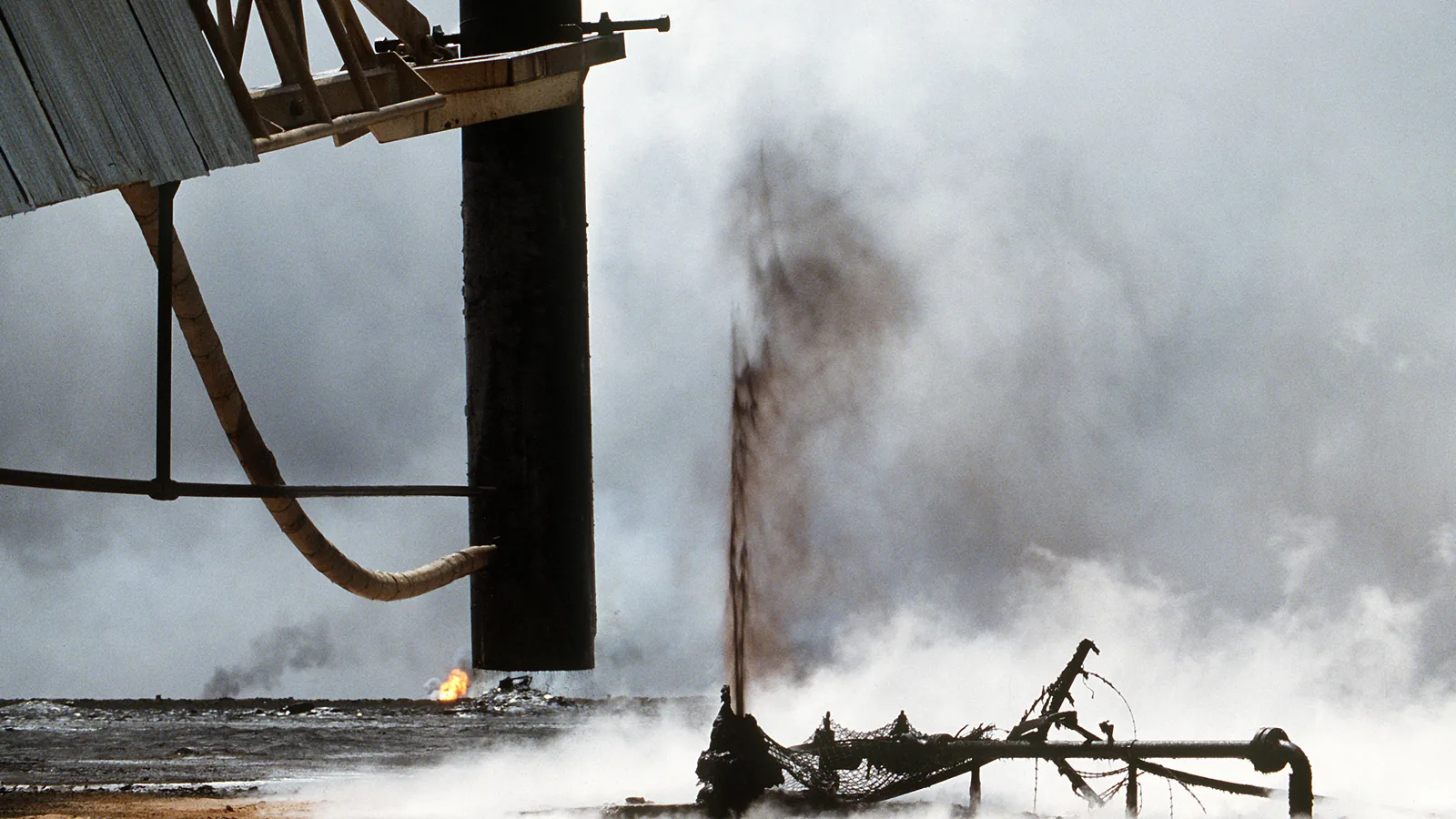 Firefighters use a crane to lift a capping device off an extinguished oil well