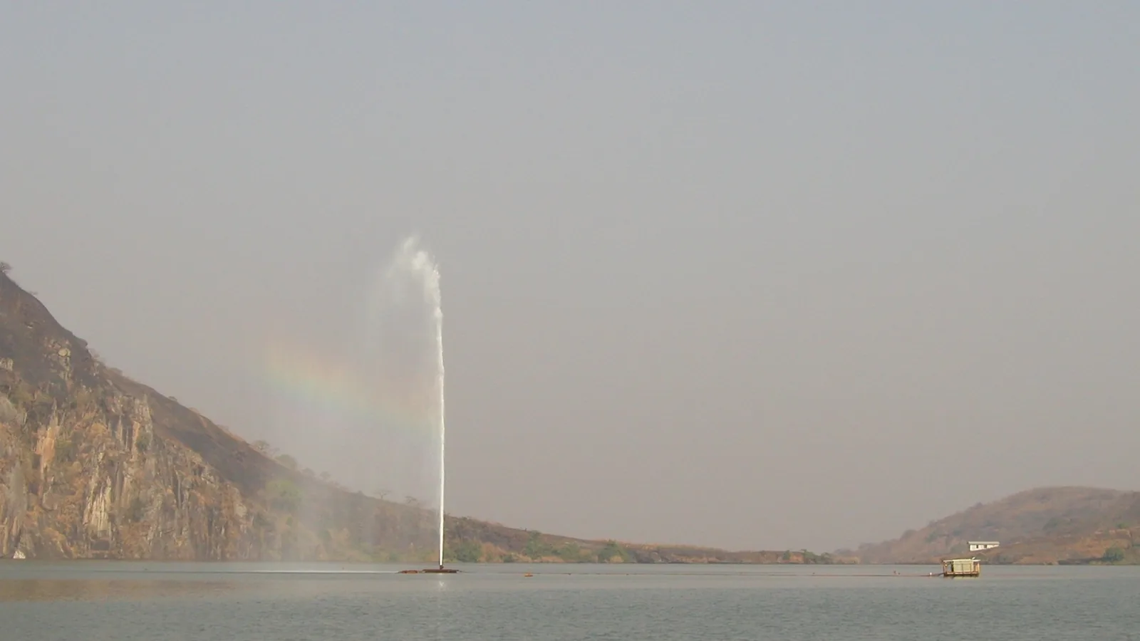 Fountain of water spraying upward from a pipe installed in a lake