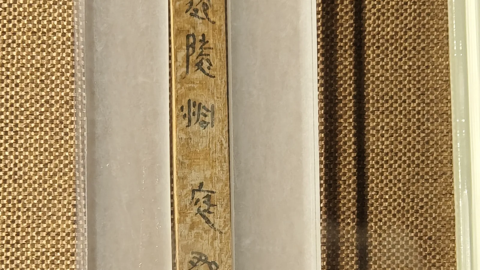 Museum case with a narrow wooden slip inscribed with the characters for Dongting commandery and Qianling county