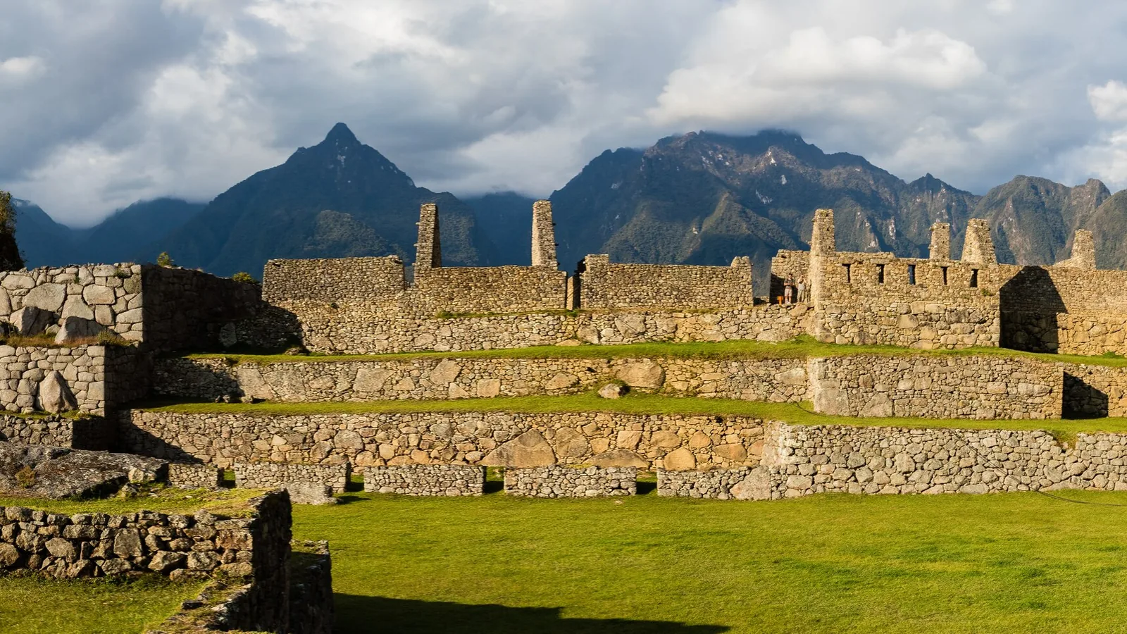 Panoramic view of stone terraces and ruins of Machu Picchu surrounded by green Andean peaks