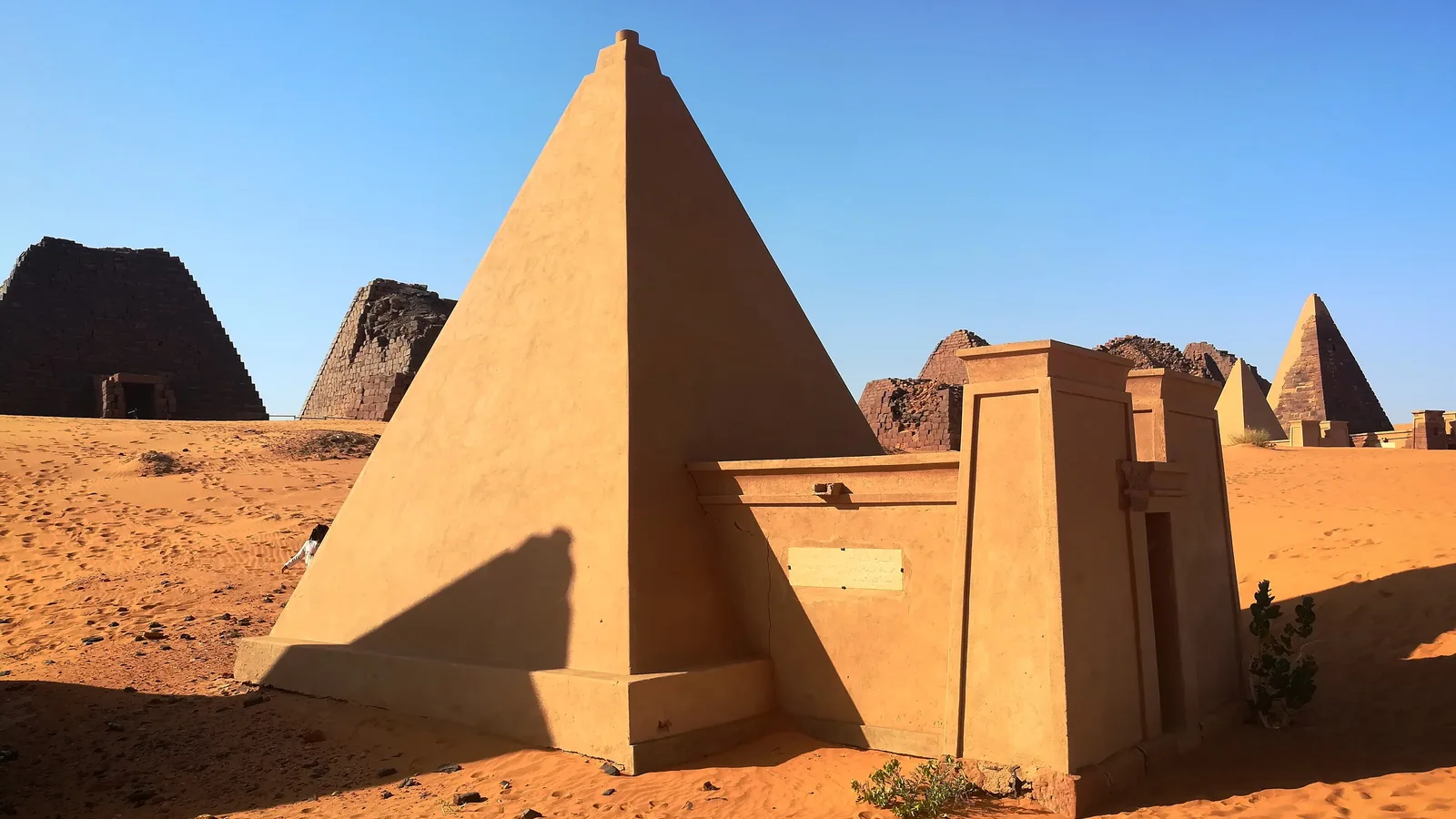 Row of steep stone pyramids in a desert landscape under a clear sky