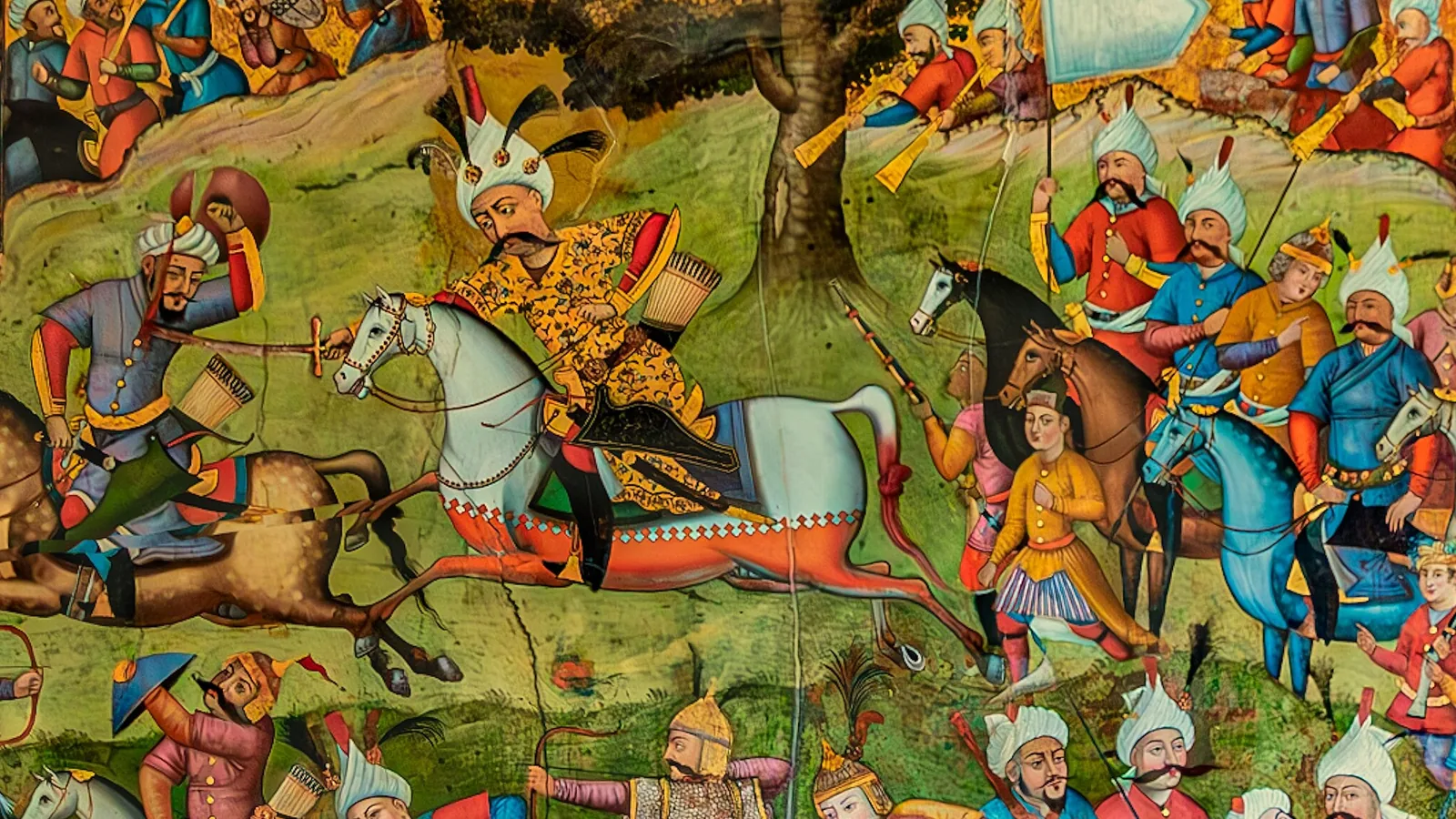 a wide Persian wall painting of mounted warriors in red caps and turbans clashing with swords and bows on a green field below a tree