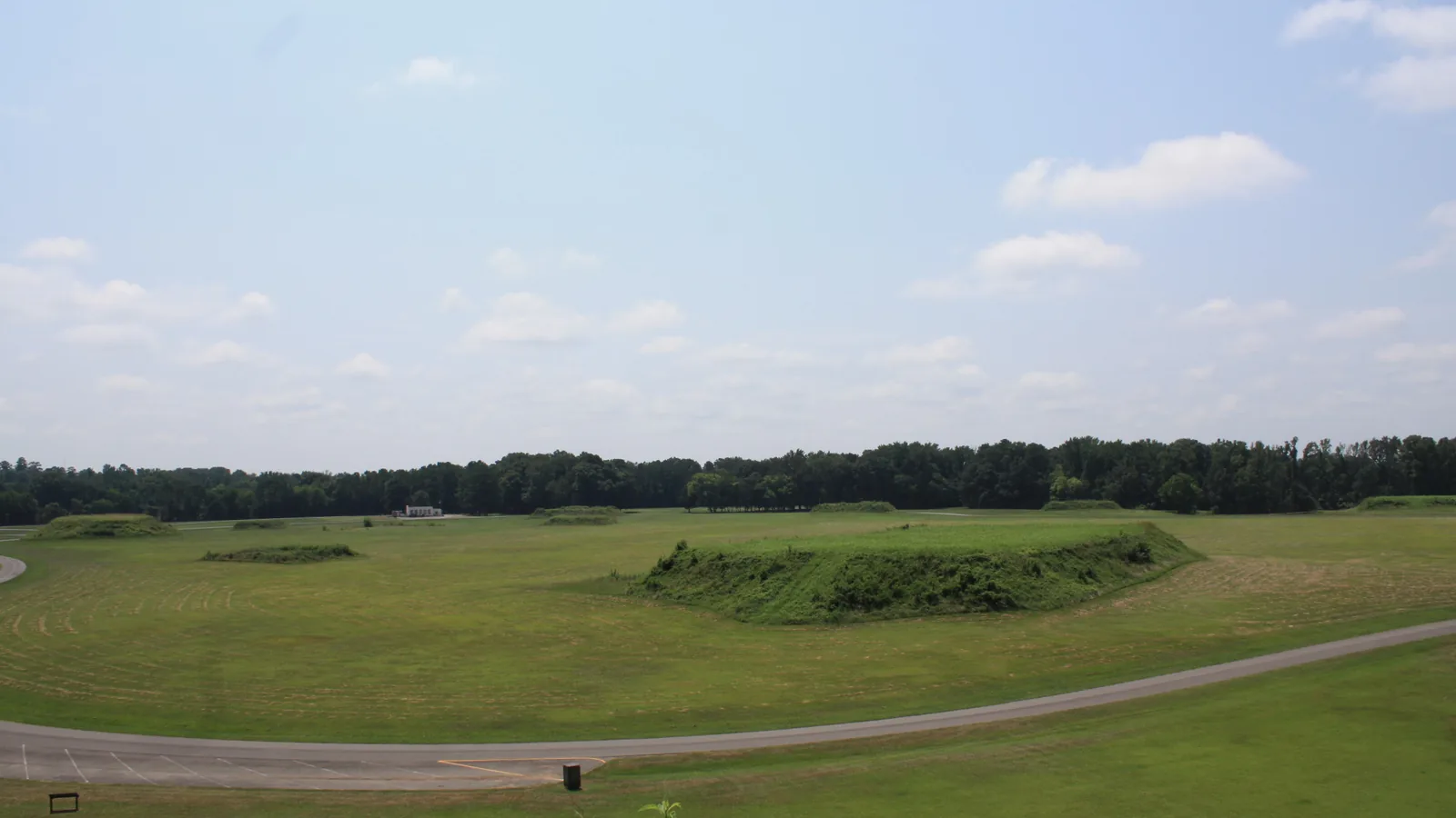 View across the grass plaza and a low mound, seen from the top of Mound B