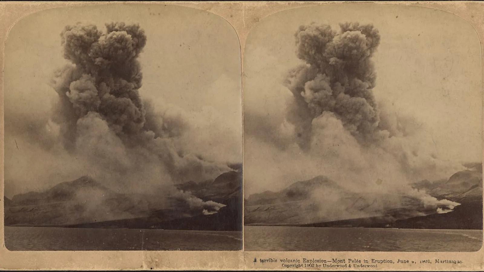 Black-and-white stereo photograph of a towering ash cloud rising from an erupting volcano above the sea