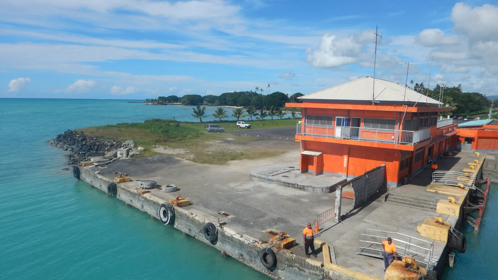 Aerial view of a concrete ferry wharf jutting into turquoise lagoon water