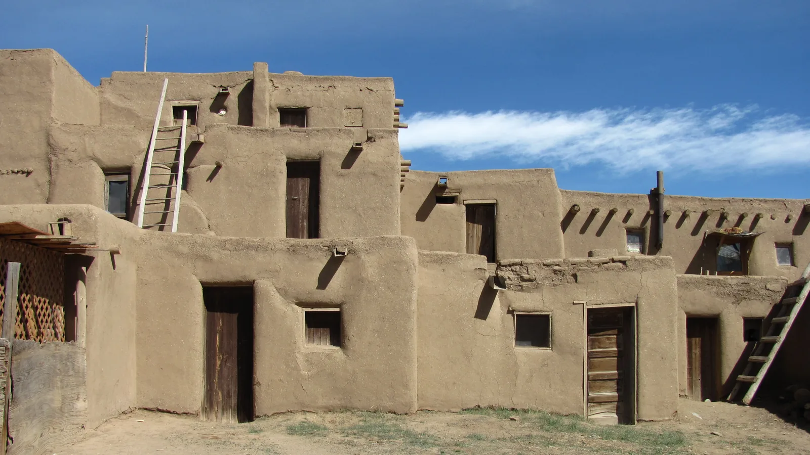 Multistoried adobe pueblo structure with ladders and small windows at Taos Pueblo, New Mexico