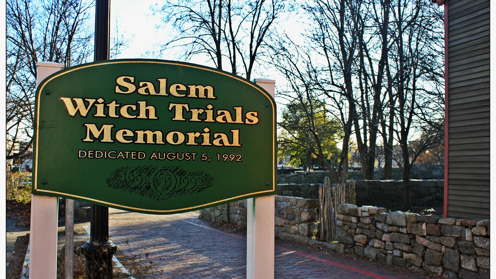 Low stone wall with inscribed granite benches in a small grassy memorial park