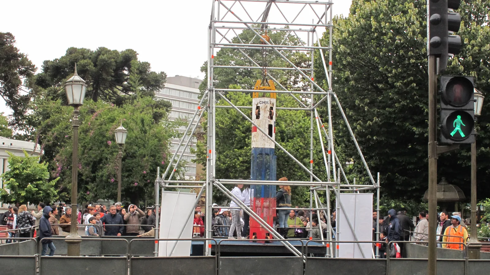 Narrow cylindrical metal rescue capsule displayed upright outdoors