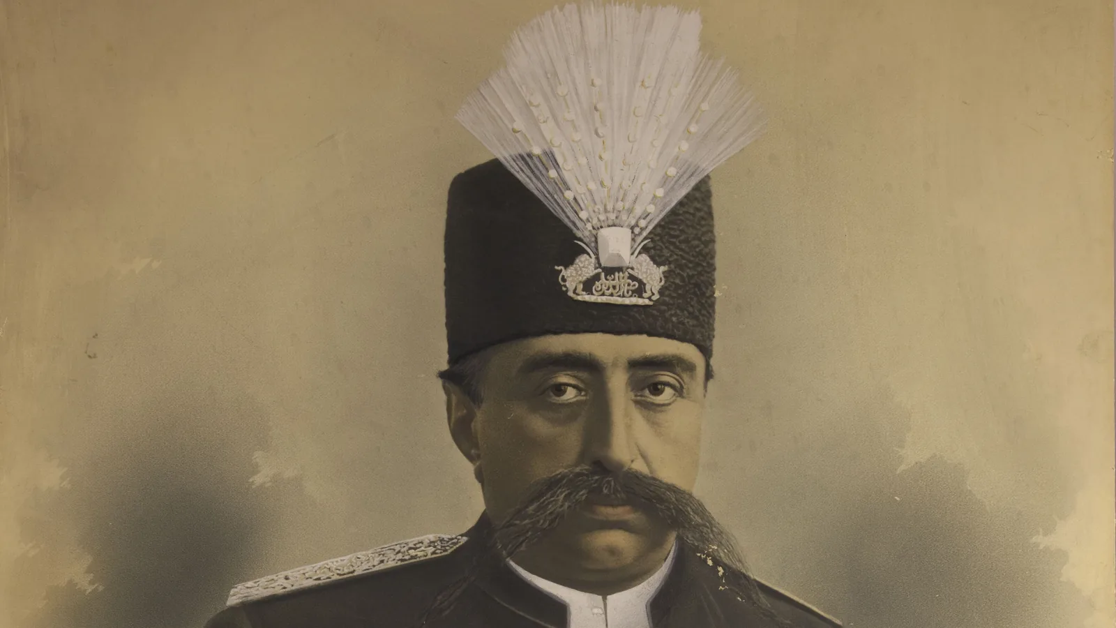 a tinted studio portrait of a man with a heavy dark mustache in a black lambskin cap with a jeweled white plume