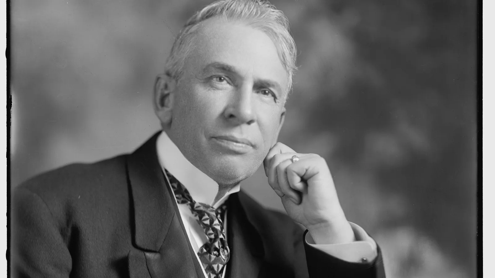Formal studio portrait of a seated man in a suit