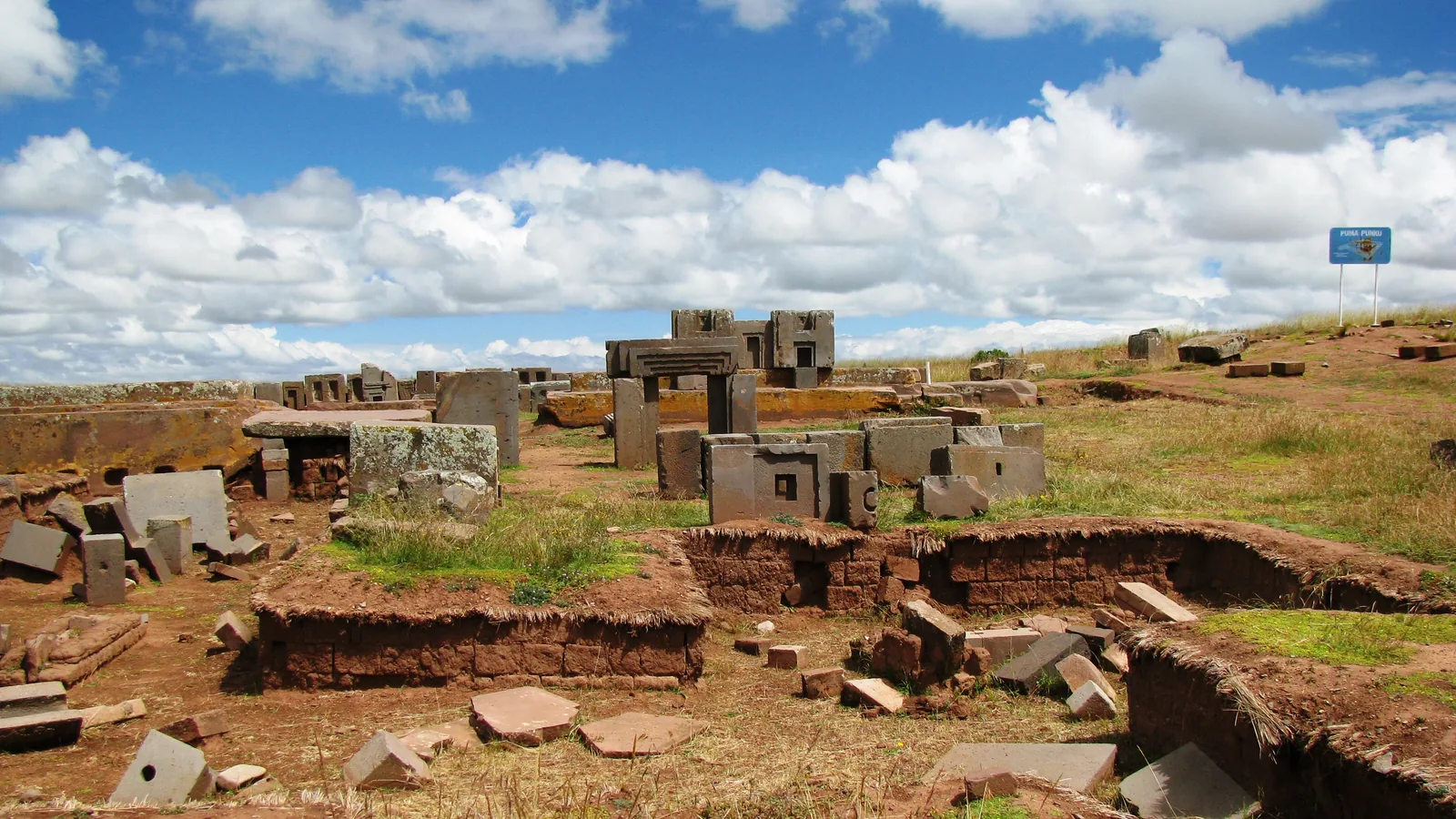 Precisely cut andesite and sandstone blocks scattered at the Pumapunku platform under a blue sky