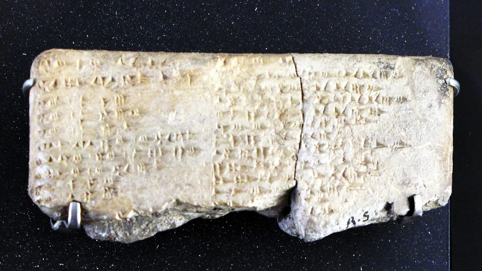 a rectangular clay tablet, cracked in two, covered with columns of cuneiform text