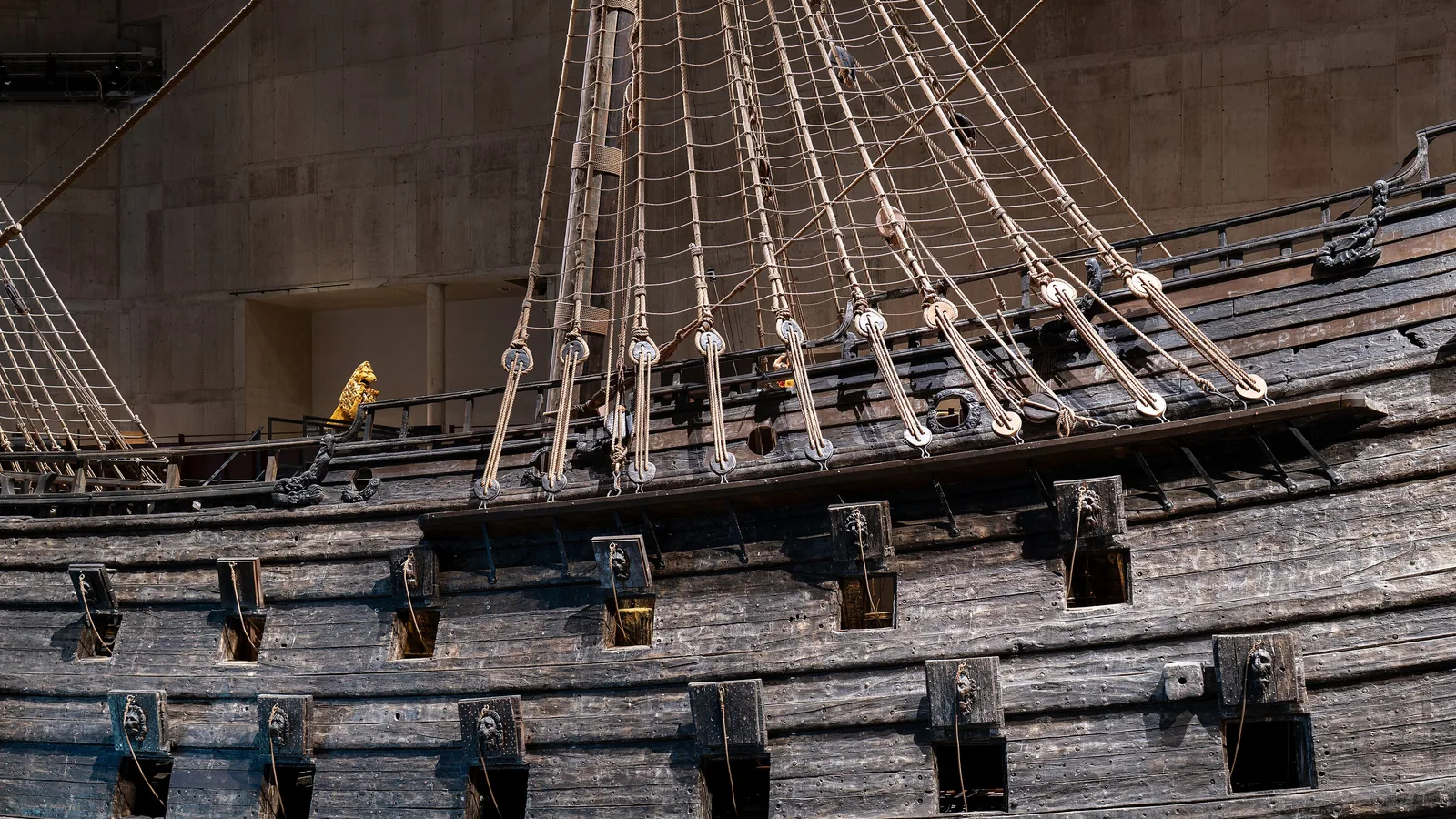 Full lateral view of a large carved wooden warship displayed inside a museum hall