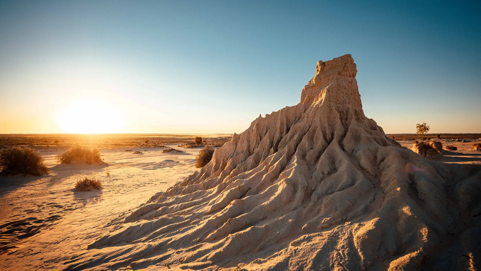 Sand-and-clay lunette pinnacle rising from a desert plain at sunset, Mungo National Park