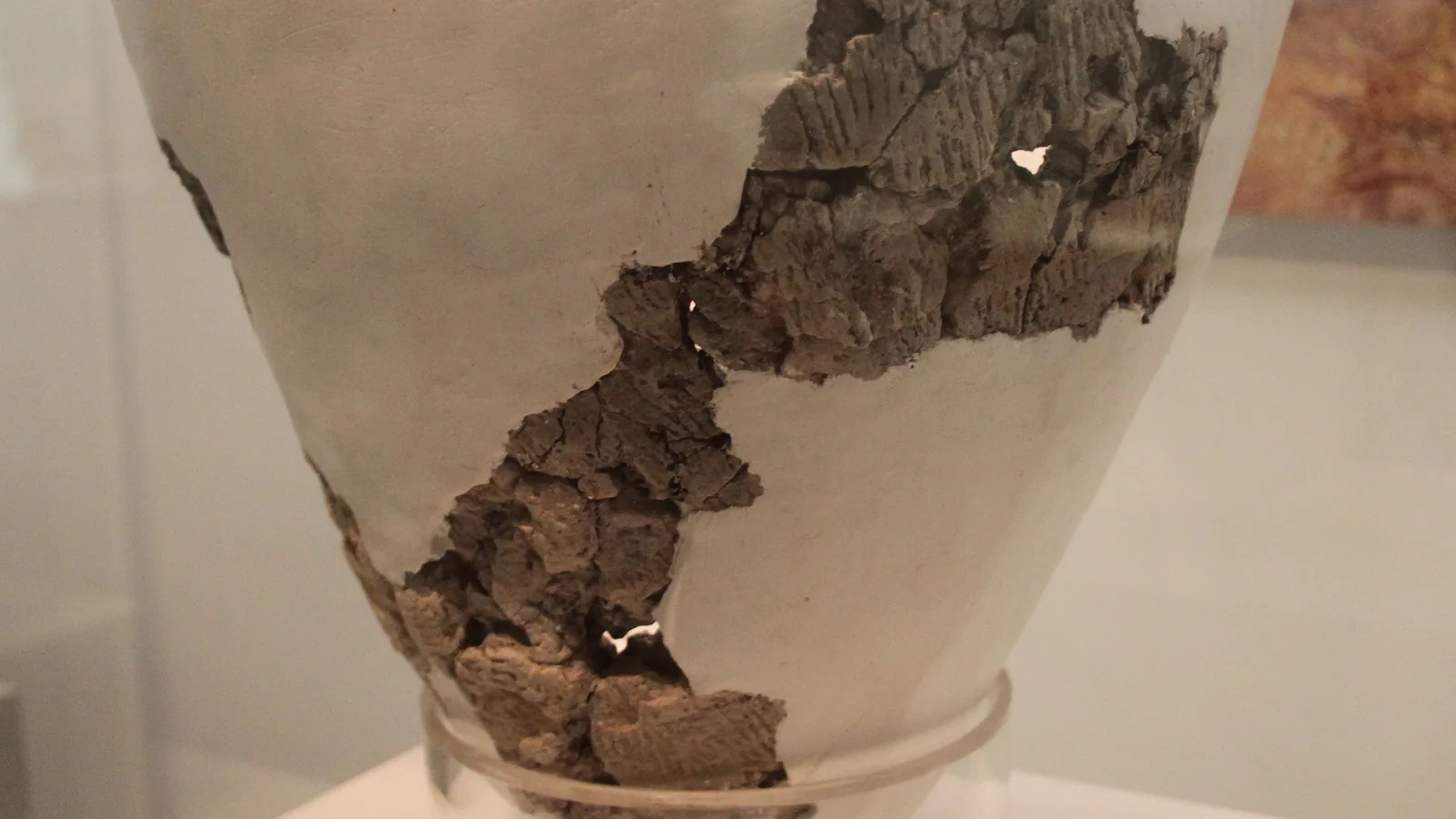the body of a reconstructed conical clay pot, pale plaster filling the gaps between dark original sherds